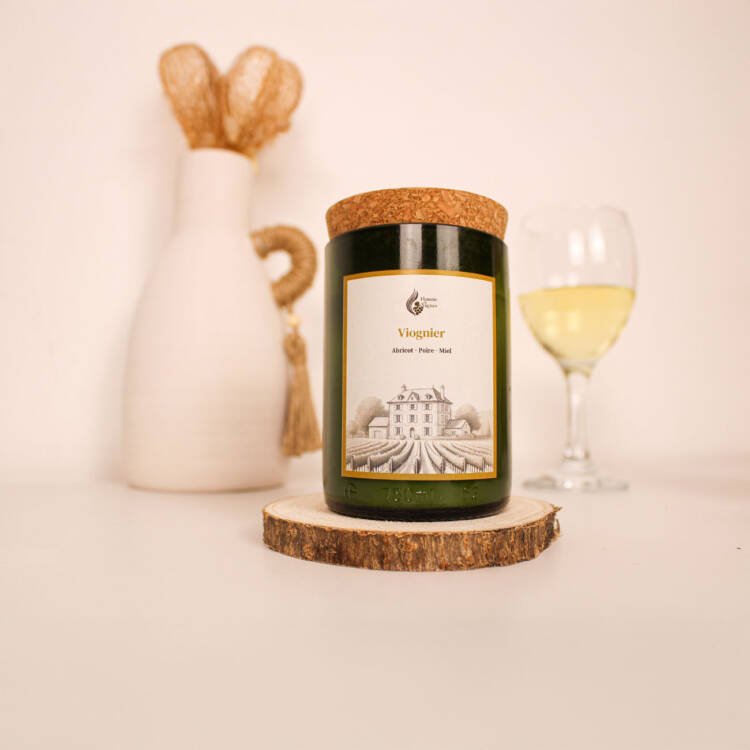 Bougie parfumée artisanale posée sur une table en bois, entourée d’abricots et de fleurs de chèvrefeuille.