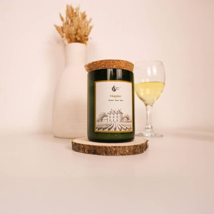 Bougie parfumée artisanale infusée des arômes du cépage Viognier, présentée avec des grappes de raisin blanc.