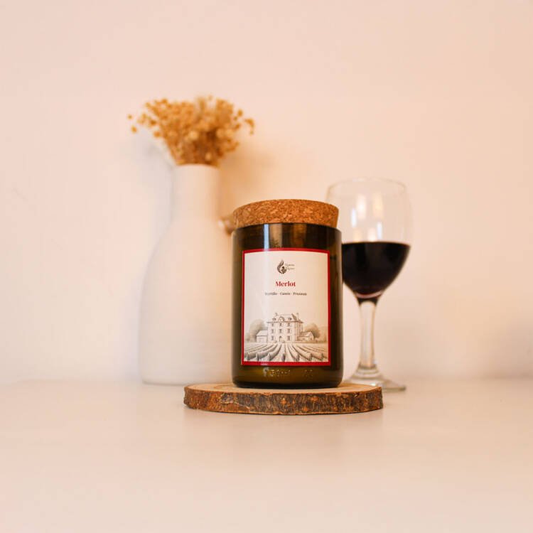 Bougie naturelle parfumée vin Merlot sur une table en bois, diffusant un parfum envoûtant.