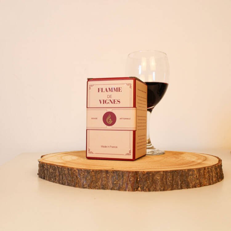 Lumière tamisée et éclat du verre recyclé, mettant en valeur la bougie parfumée vin Merlot.